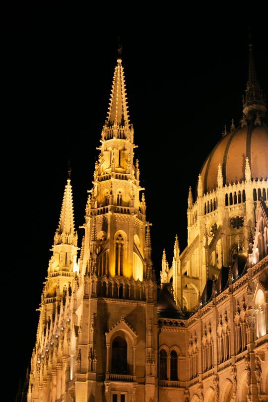 The Hungarian Parliament building lit up at night with a warm glow and dark night