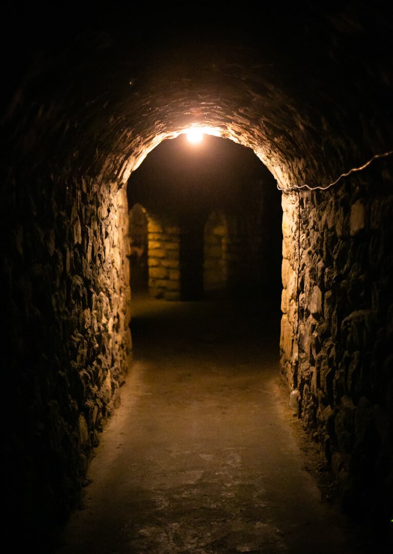 Dark stone tunnel inside the Buda Castle Labyrinth in Budapest, where Vlad the Impaler was reportedly imprisoned, connected to Dracula legends and dark tourism.
