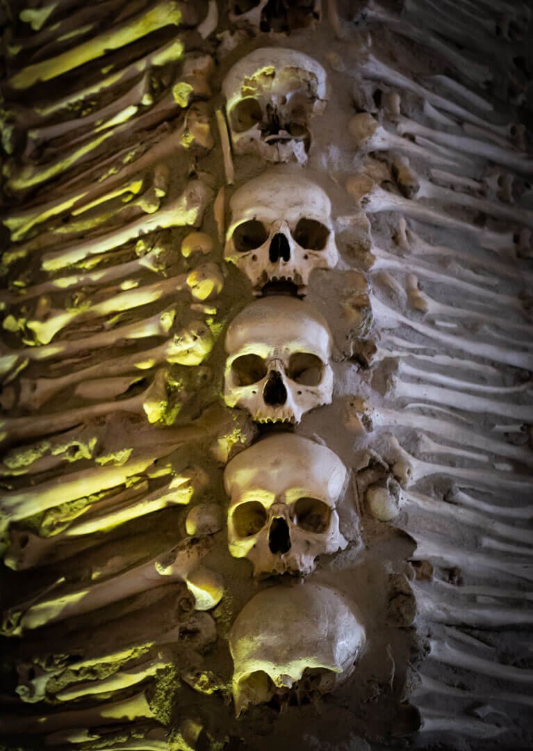 Close-up of human skulls and bones covering the walls of Capela dos Ossos in Évora, Portugal, a famous dark tourism and dark history site