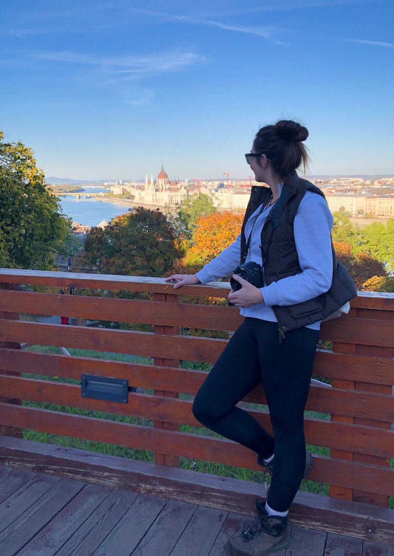 Solo female traveller overlooking the Danube River and Budapest skyline while exploring the city's dark history and cultural heritage.
